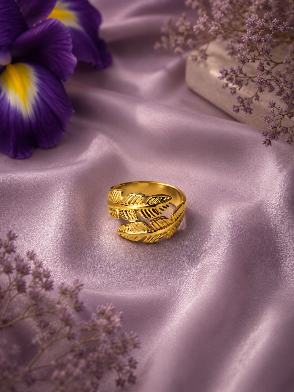 Gold leaf-wrap adjustable ring displayed on lavender satin fabric with purple floral accents.
