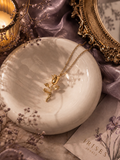Golden Rose Bloom pendant necklace with elegant gold rose flower pendant displayed on a marble tray.